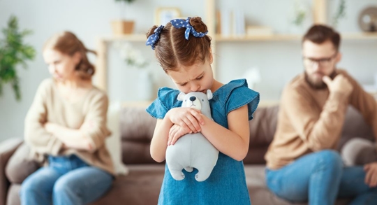 Parental Alienation - little girl holds stuffed animal while parents sit on either side of the couch