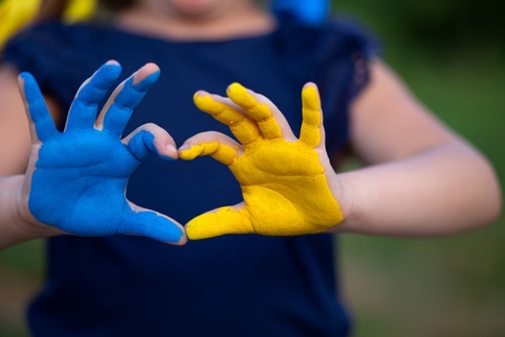 Child with hands painted in the colors of Ukraine in the shape of a heart
